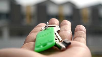 Hånd, der holder en nøgle. Nøglen har en grøn nøglering.